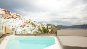 Una piscina en la azotea con vistas a edificios blancos y un cielo azul.