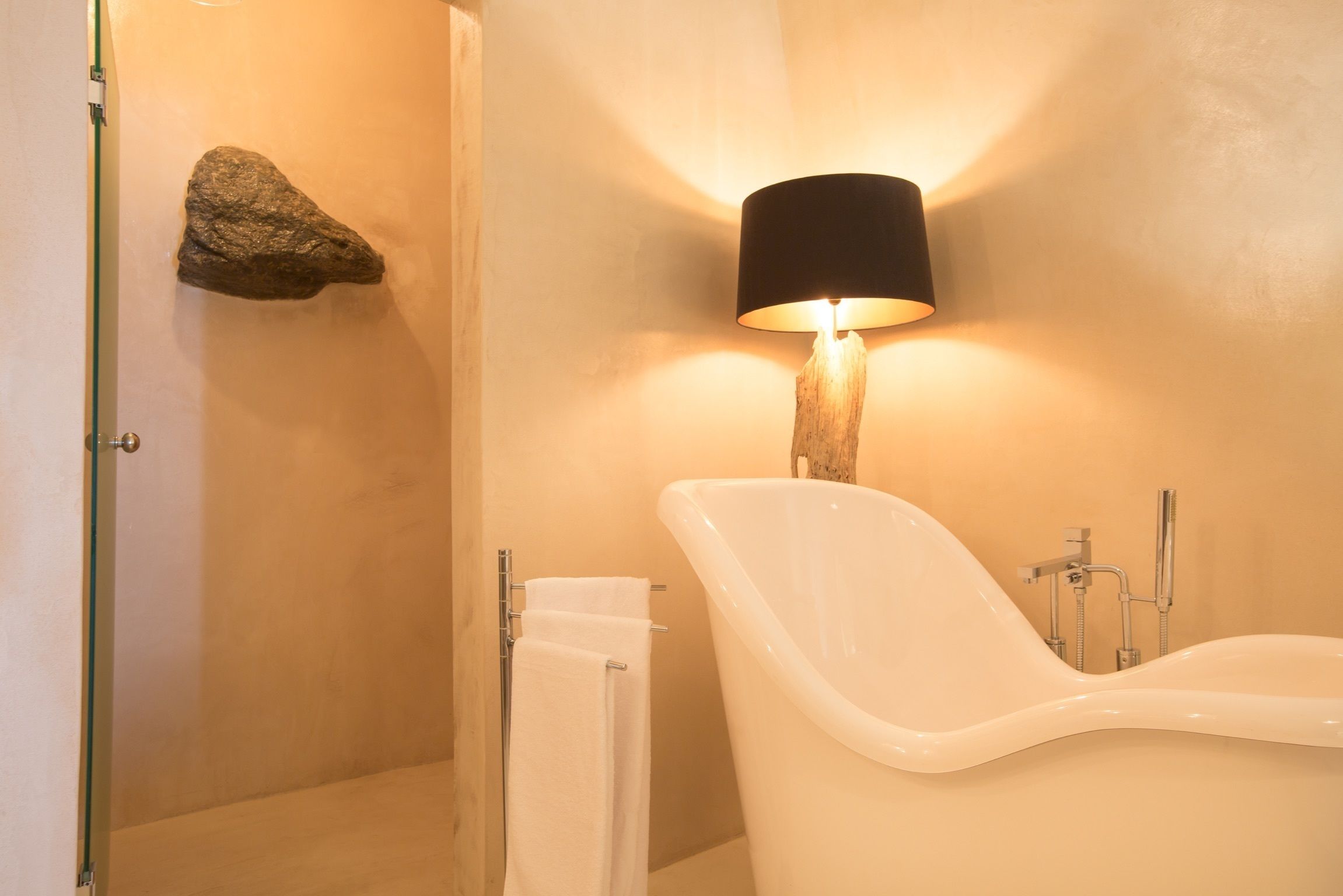 A bathroom with a bathtub, a shower, a towel rack, and a wall-mounted lamp.