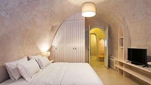 Un dormitorio con cama, mesitas de noche, televisor y armario.