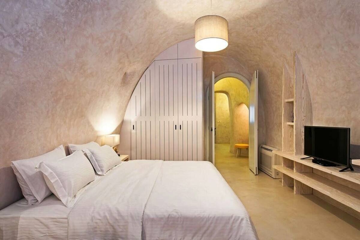A bedroom with a bed, bedside tables, a TV, and a wardrobe.