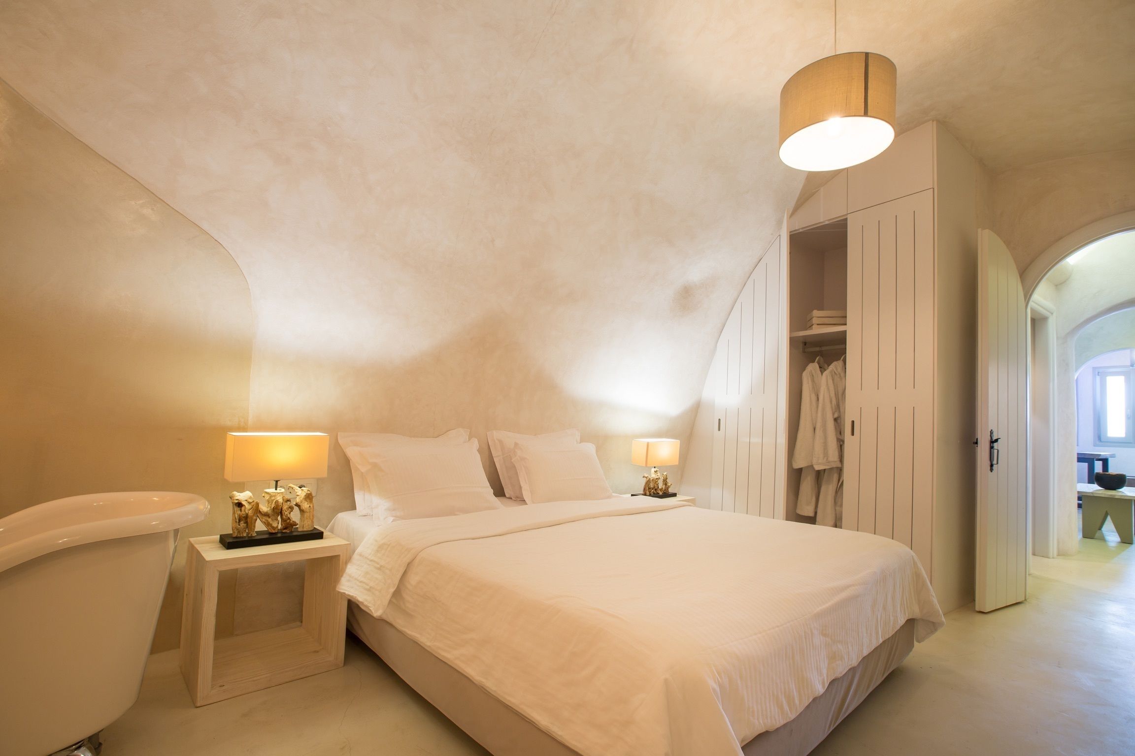 Een slaapkamer met een groot bed, nachtlampjes, een kledingkast en een badkamer.