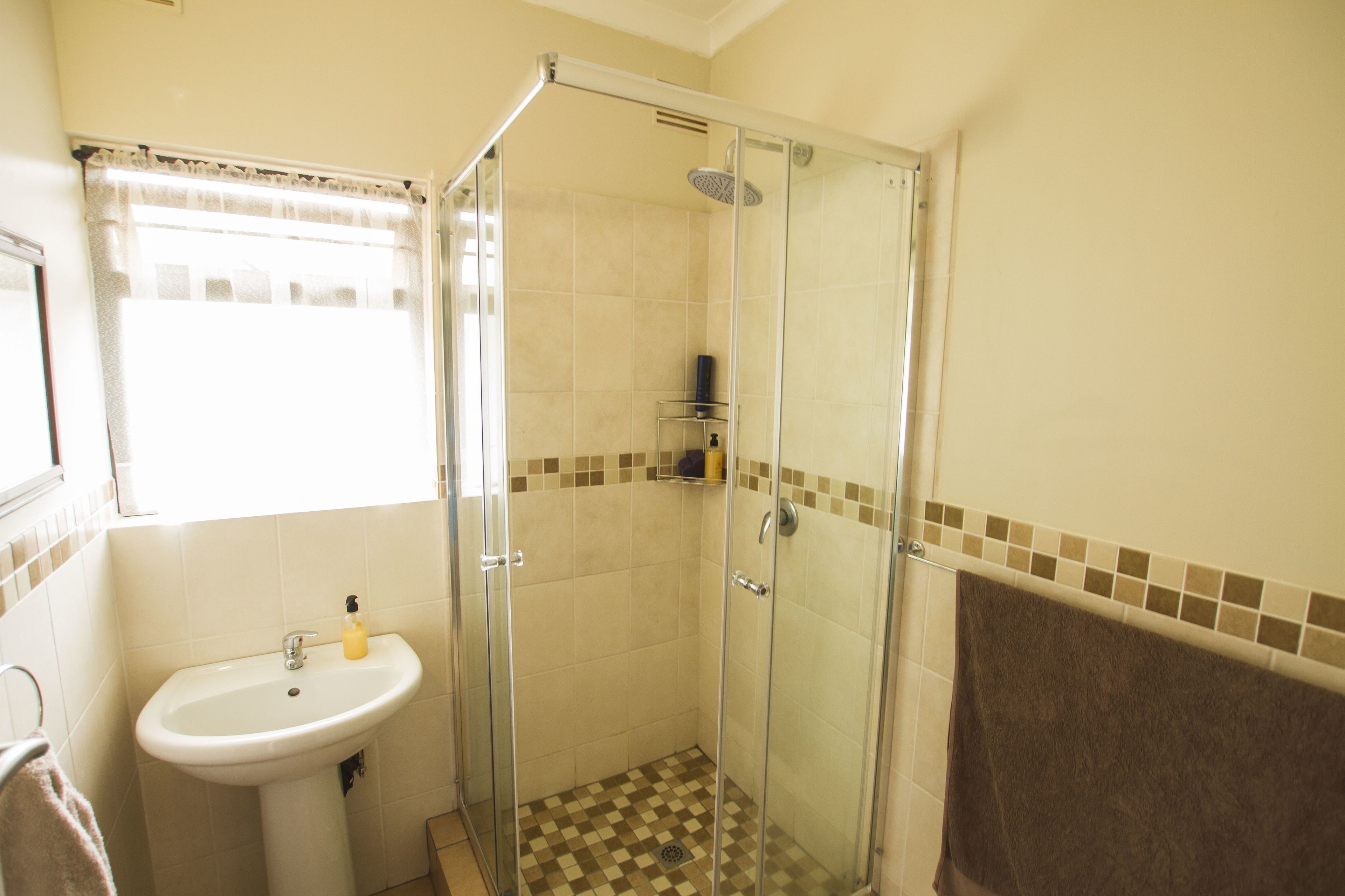 A bathroom with a glass-enclosed shower, a sink, and a towel rack.