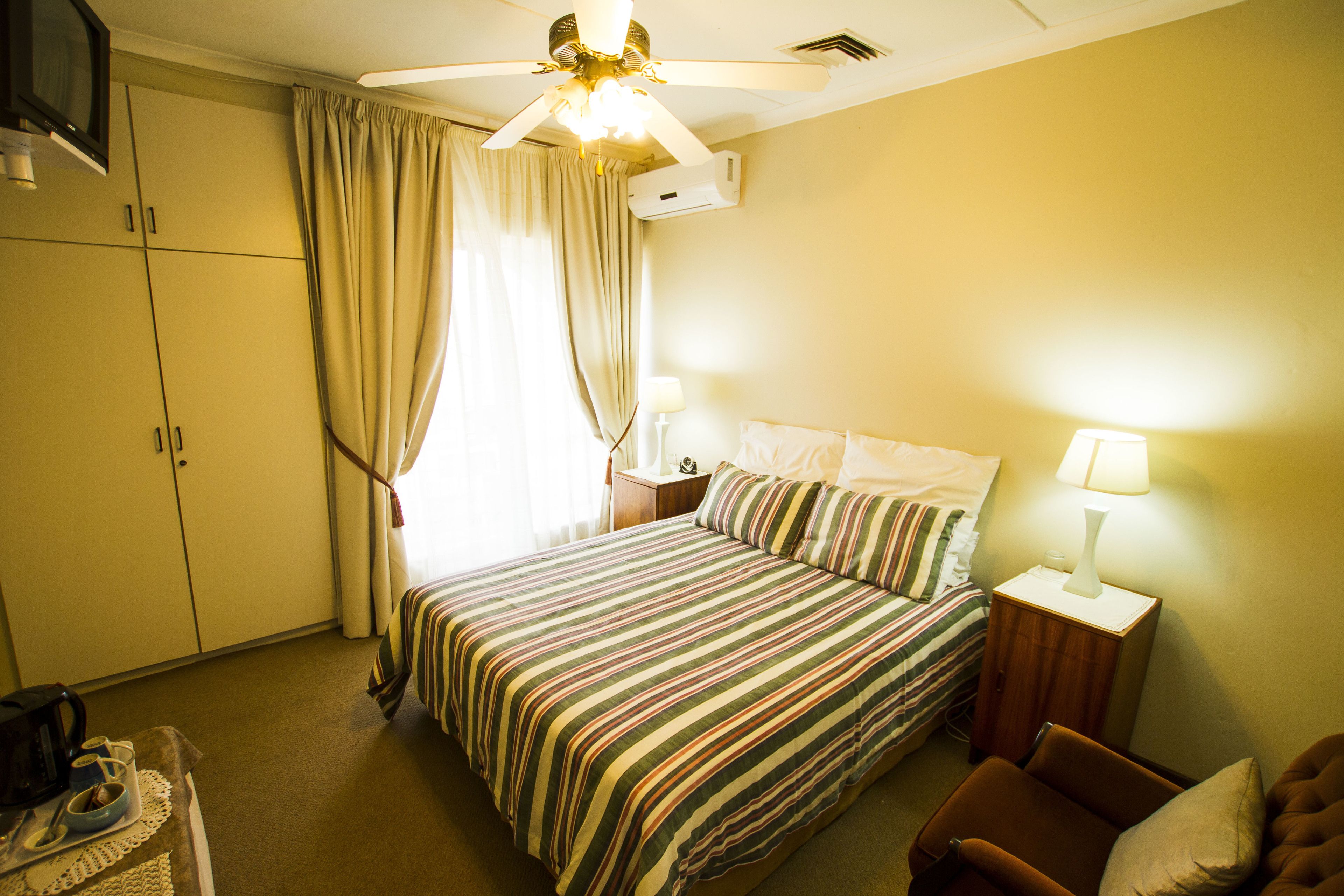 A hotel room with a bed, a chair, a nightstand, a TV, and curtains.