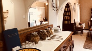 A hotel room with a large mirror, a wooden dresser, and a dining area with a table and chairs. - Eden Rose Manor (La Mercy)
