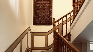 A staircase with wooden balusters and a patterned wall hanging above. - Eden Rose Manor (La Mercy)