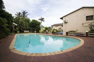 Una piscina al aire libre, sillones reclinables de piscina