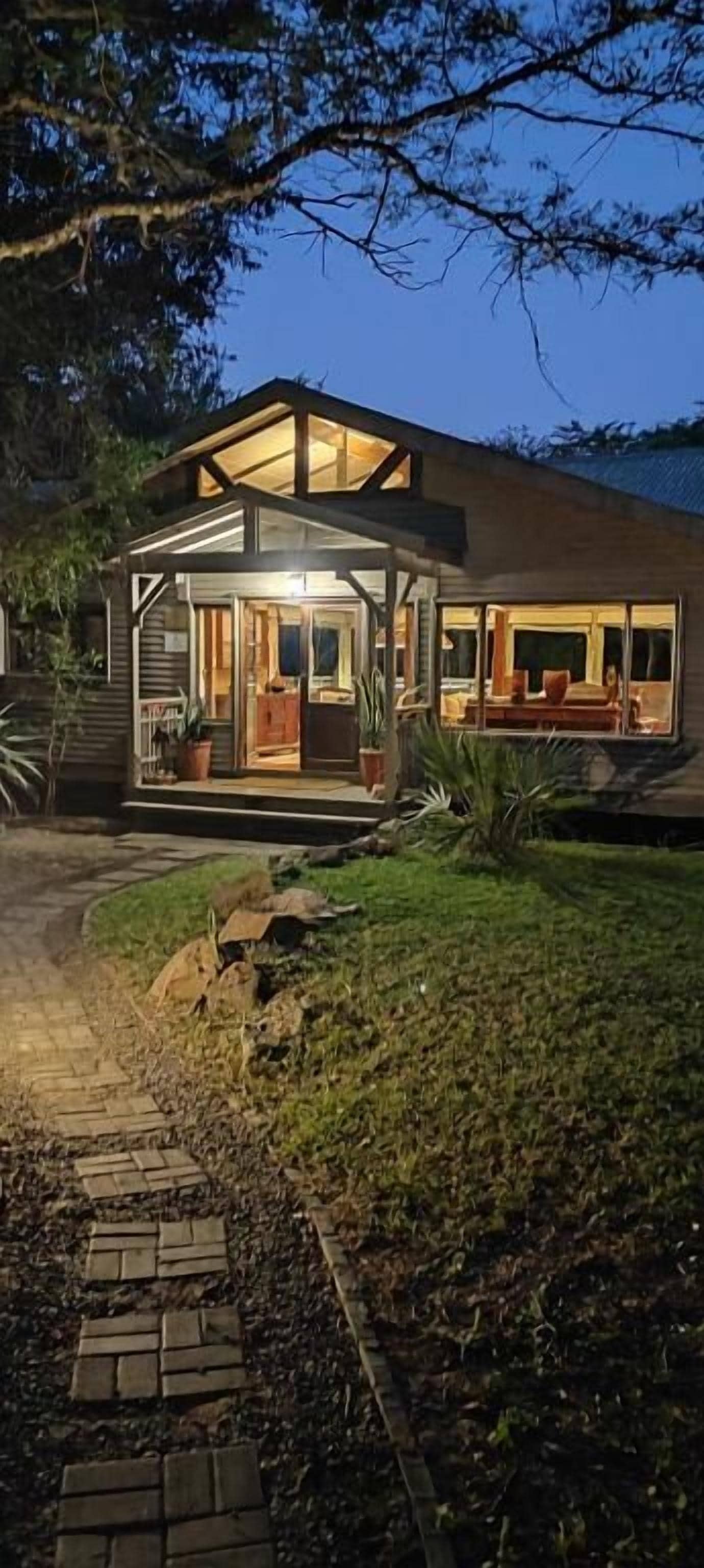 A modern house with a glass extension, a paved driveway, and a well-maintained lawn.