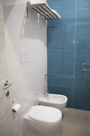 Ein Badezimmer mit Toilette, Bidet und Handtuchhalter.