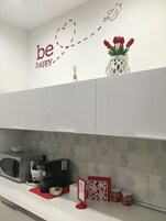 A kitchen with white cabinets, a microwave, a coffee maker, and a vase with red tulips.