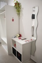 A white vanity with a mirror, a small plant, and a few items on the counter.