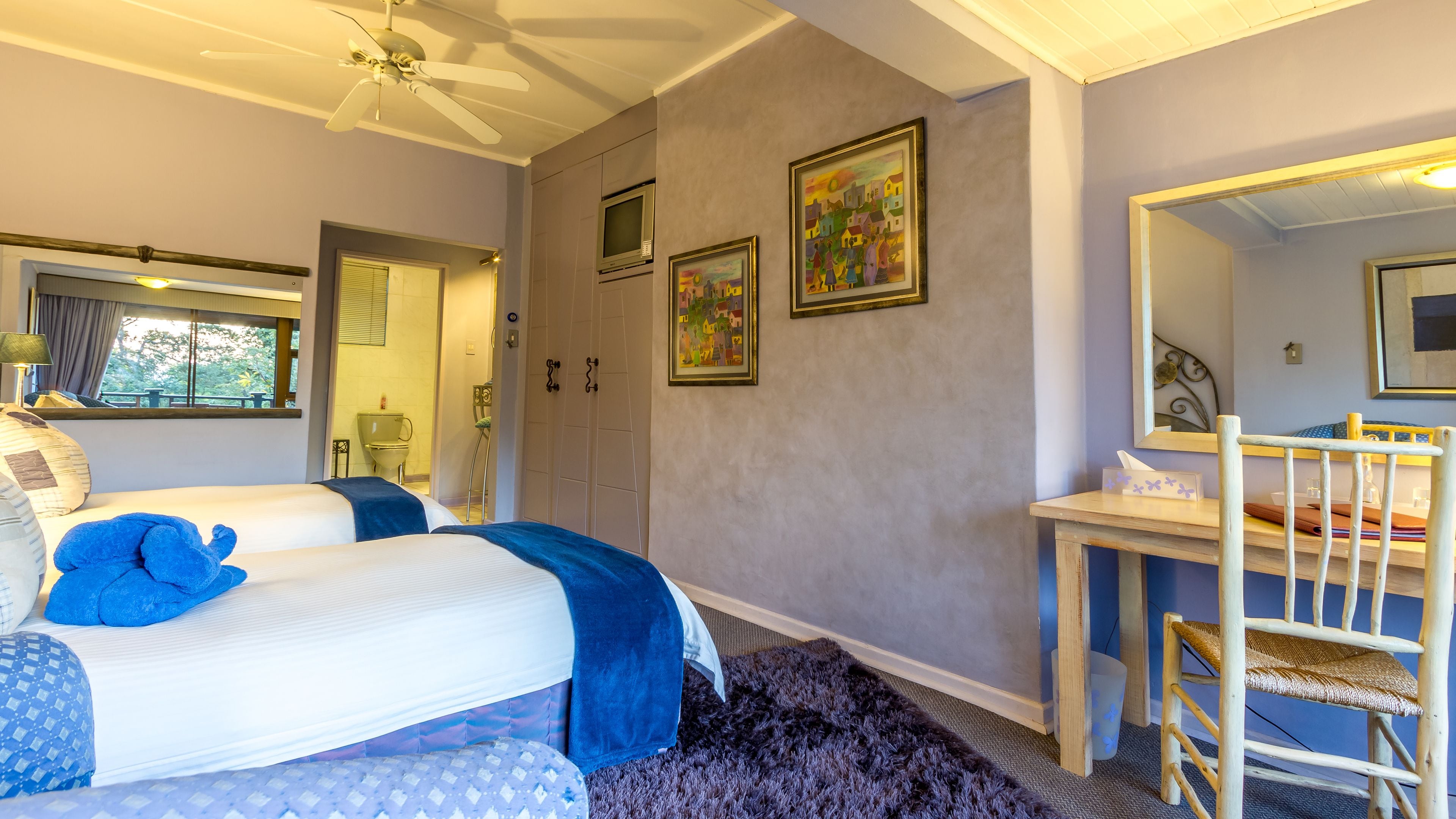 A bedroom with two beds, a desk, a chair, and a shower area.