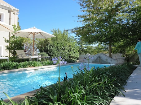 Una piscina al aire libre, sillones reclinables de piscina