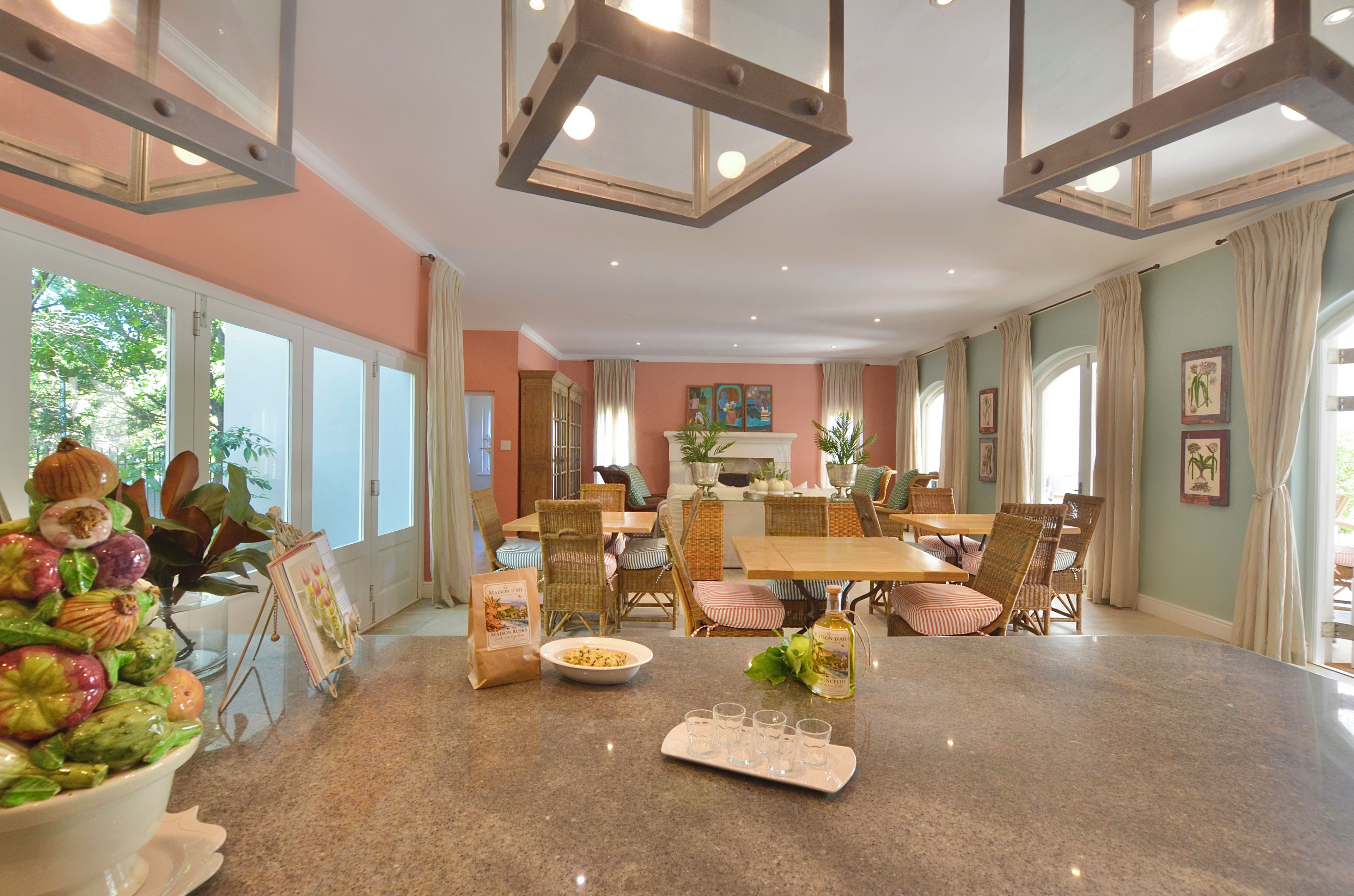 Un vaste espace dédié à la salle à manger, avec une grande table en granit, des chaises en osier et une vue sur l’extérieur grâce à de grandes fenêtres.