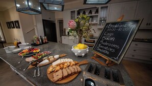 Un buffet de petit-déjeuner proposant une grande variété d’aliments, avec un tableau noir affichant la liste des plats disponibles.