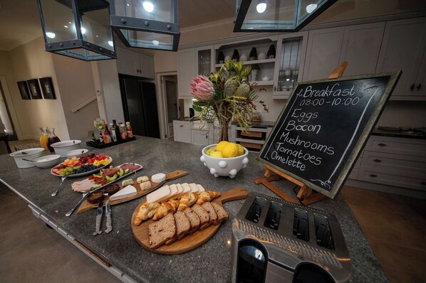 A breakfast buffet with a variety of foods and a chalkboard menu listing breakfast items.