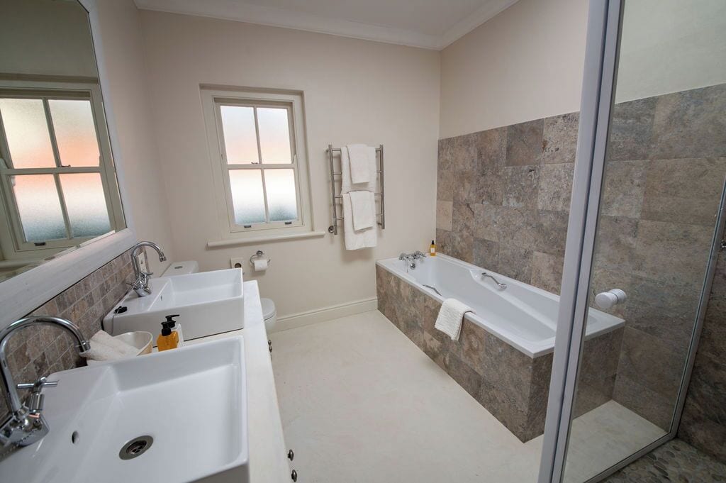 Une salle de bain moderne avec deux lavabos, une baignoire et une cabine de douche en verre.