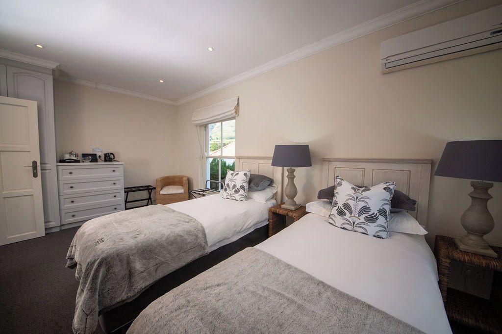 A hotel room with two beds, a dresser, a chair, and a window with curtains.