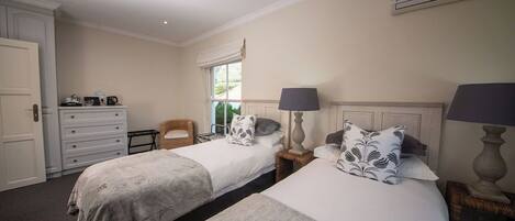 A hotel room with two beds, a dresser, a chair, and a window with curtains.
