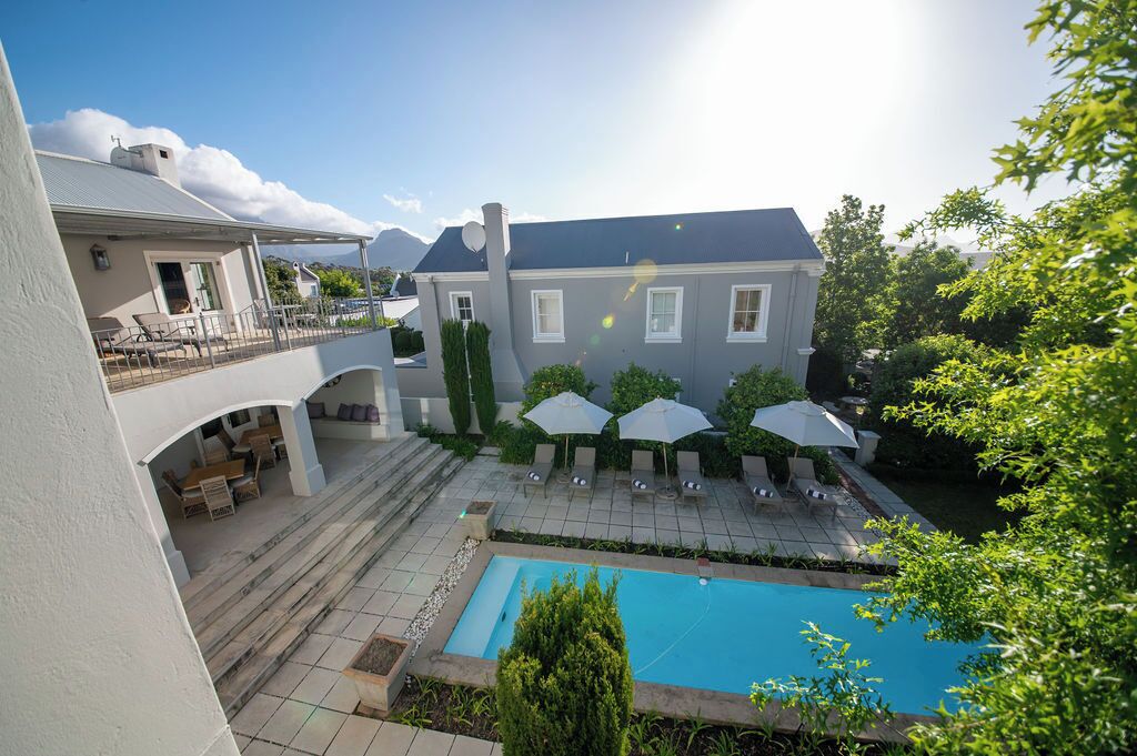 Propiedad residencial con piscina, zona de estar exterior y patio cubierto.