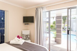Una camera d'albergo con un letto, una televisione, un bagno e vista su una piscina.