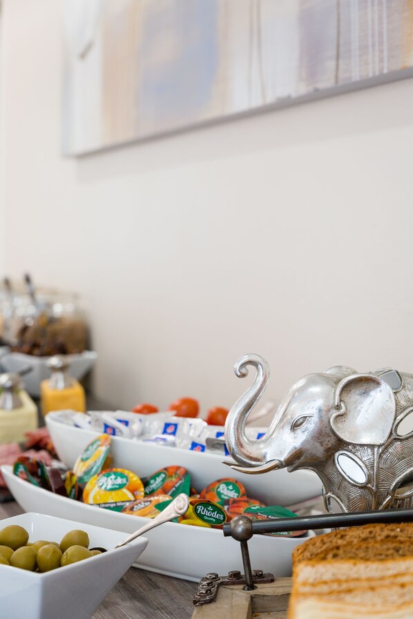 A buffet table with various food items and condiments, including olives, cheese, and packaged snacks.