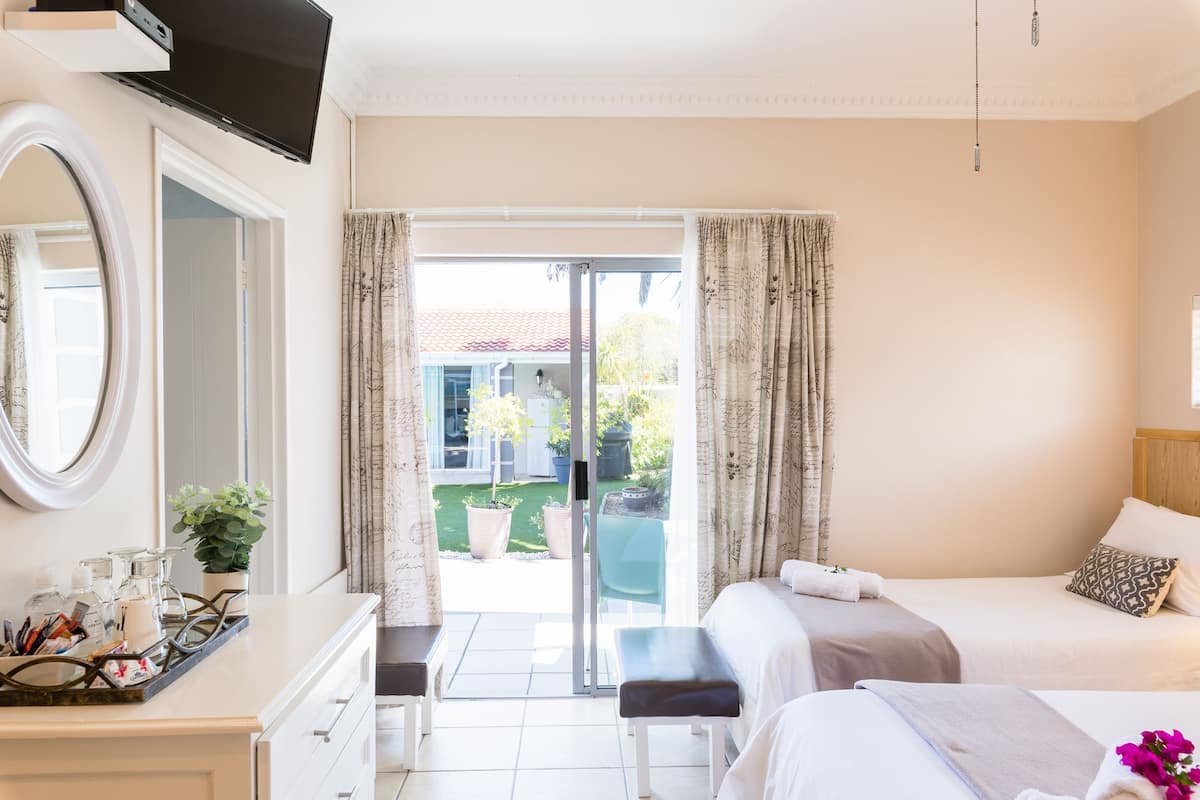 Quarto de hotel com uma cama, uma secretária com espelho e vista para o exterior.