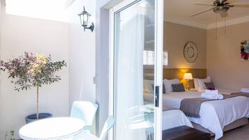 A hotel room with a bed, bedside tables, a ceiling fan, and a potted plant.