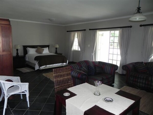 A hotel room with a bed, two sofas, a dining table, and a chair.