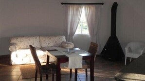 A dining area with a table, chairs, a sofa, and a guitar. - Waterwoods Cottages (Fort Nottingham)