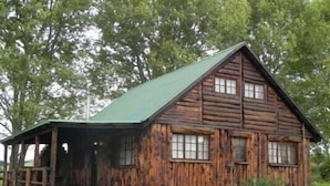 A rustic log cabin with a green roof, a porch, and a stone foundation. - Waterwoods Cottages (Fort Nottingham)