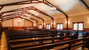 A church interior with wooden pews, a high ceiling with exposed beams, and large windows. - Waterwoods Cottages (Fort Nottingham)