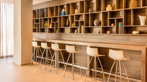 A modern bar area with a wooden shelf display and five white bar stools.