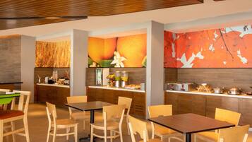 Un restaurante moderno con mobiliario de madera, una barra con productos alimenticios y una pared decorada con motivos de frutas y hojas.
