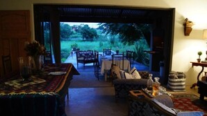 Un espace de vie à aire ouverte donnant sur un jardin. On y trouve une table à manger avec des chaises, un canapé et une table basse.