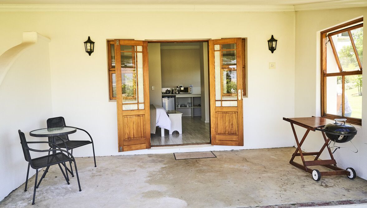 An open doorway leading to a kitchen area with a dining table and chairs outside.