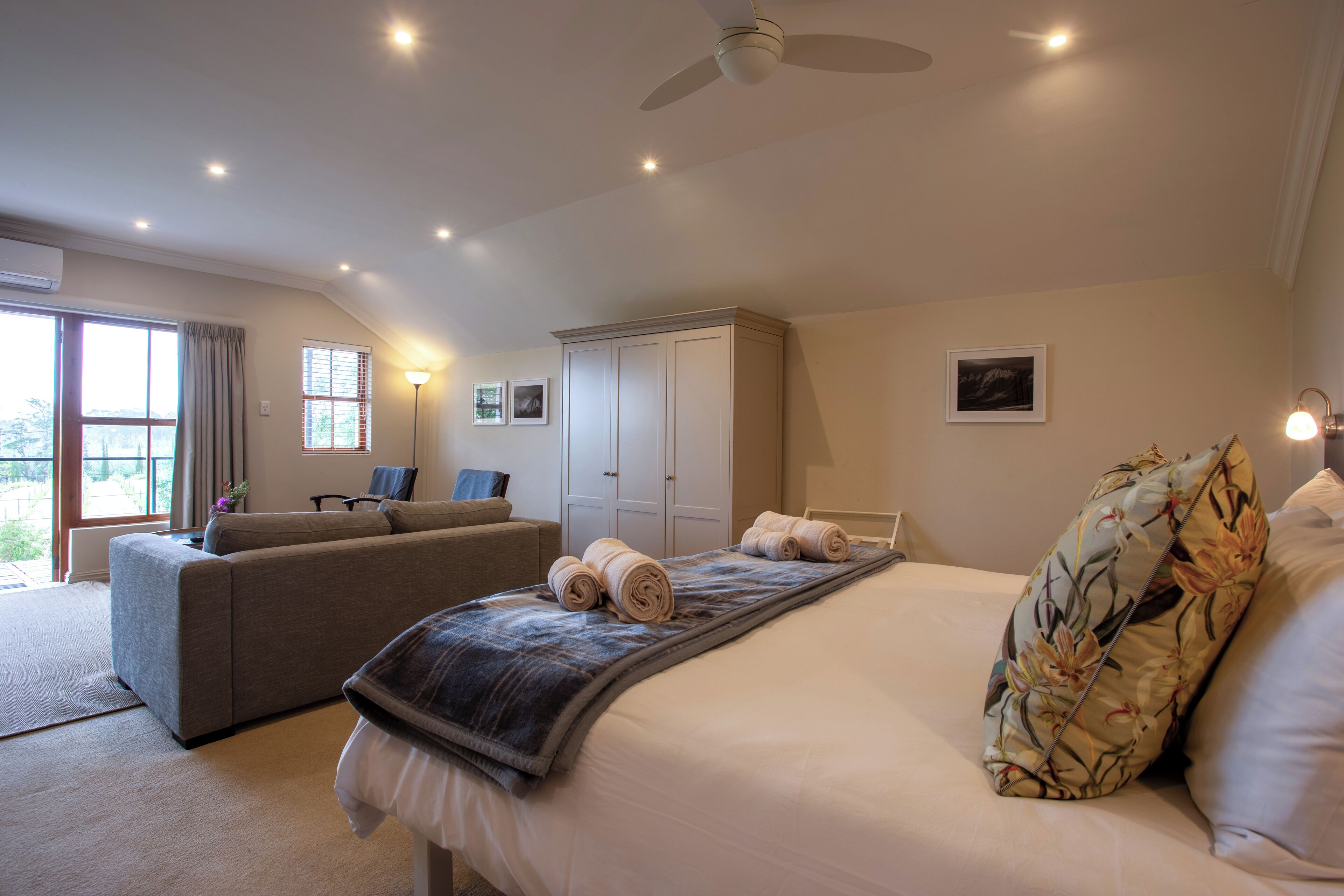 A spacious bedroom with a large bed, a sofa, and a wardrobe.
