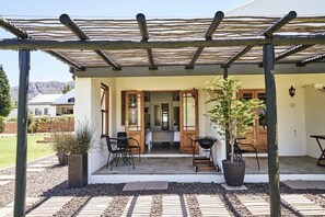 An outdoor patio with a pergola, seating, and a barbecue grill.