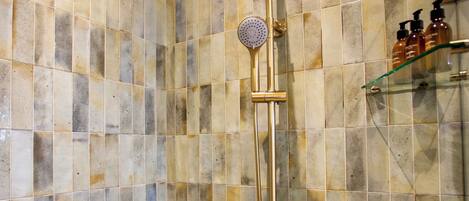A shower with a gold fixture and a tiled wall.