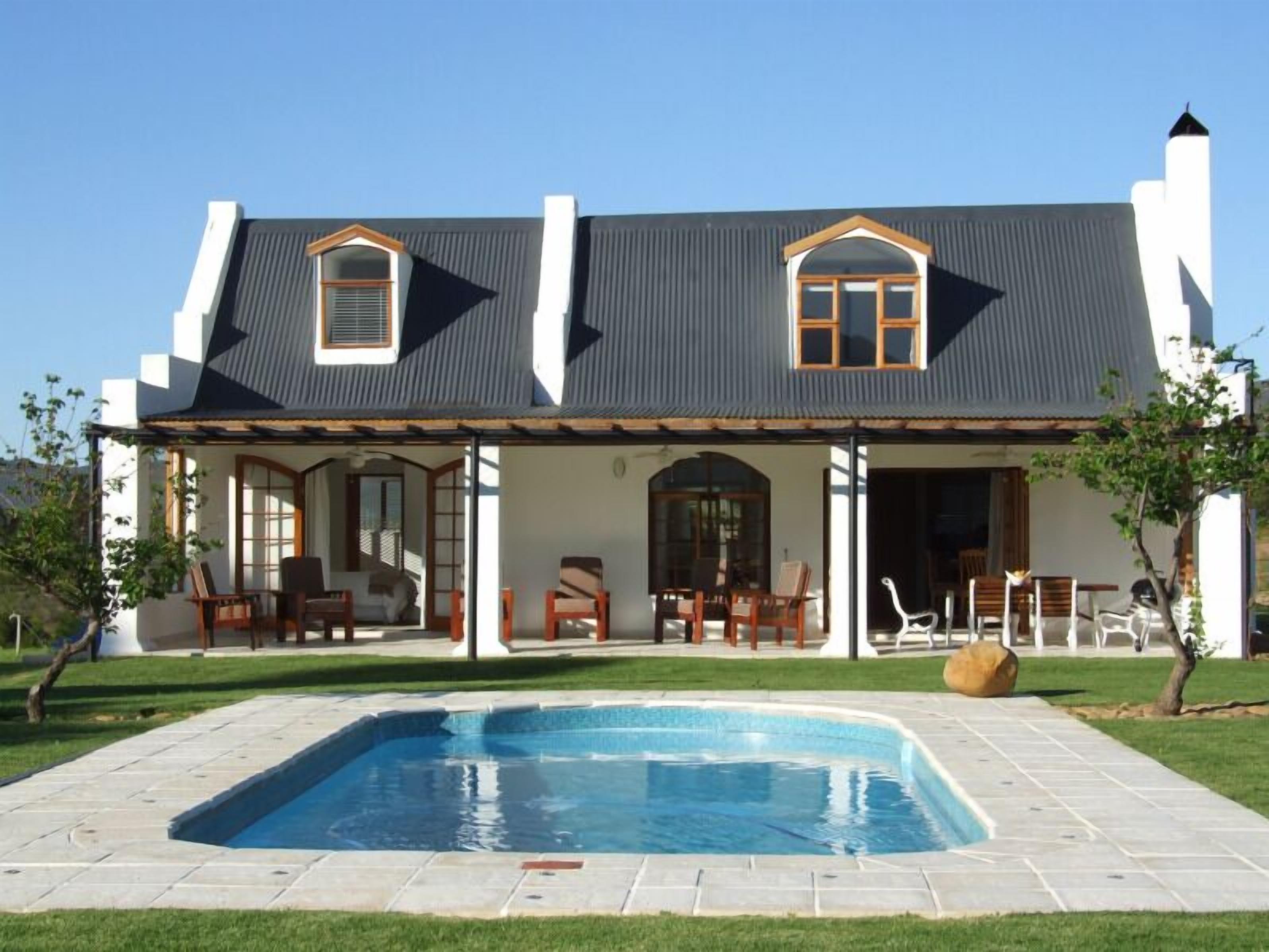 A two-story house with a covered patio, a swimming pool, and outdoor furniture.