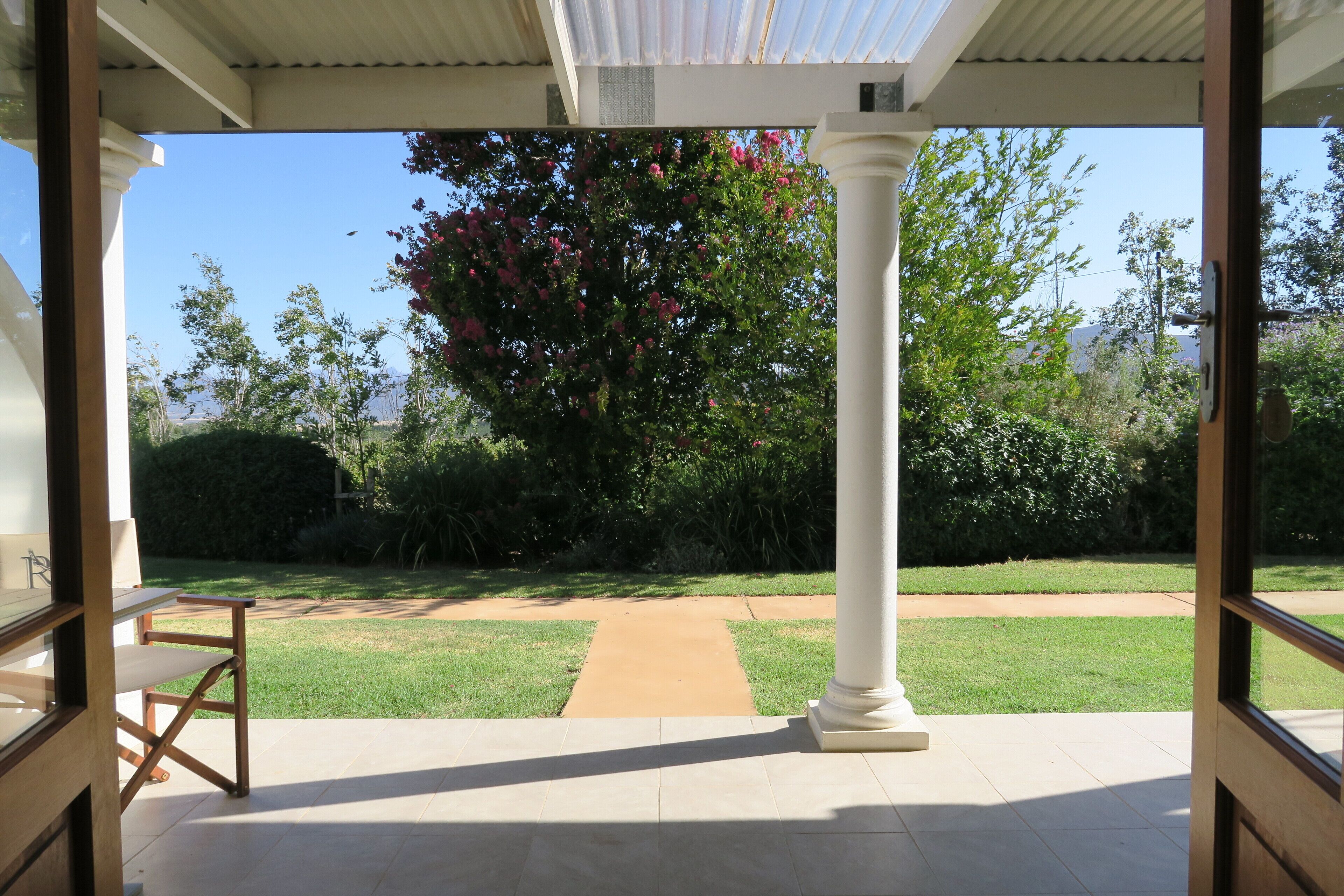 Um alpendre coberto com vista para um jardim e um caminho.