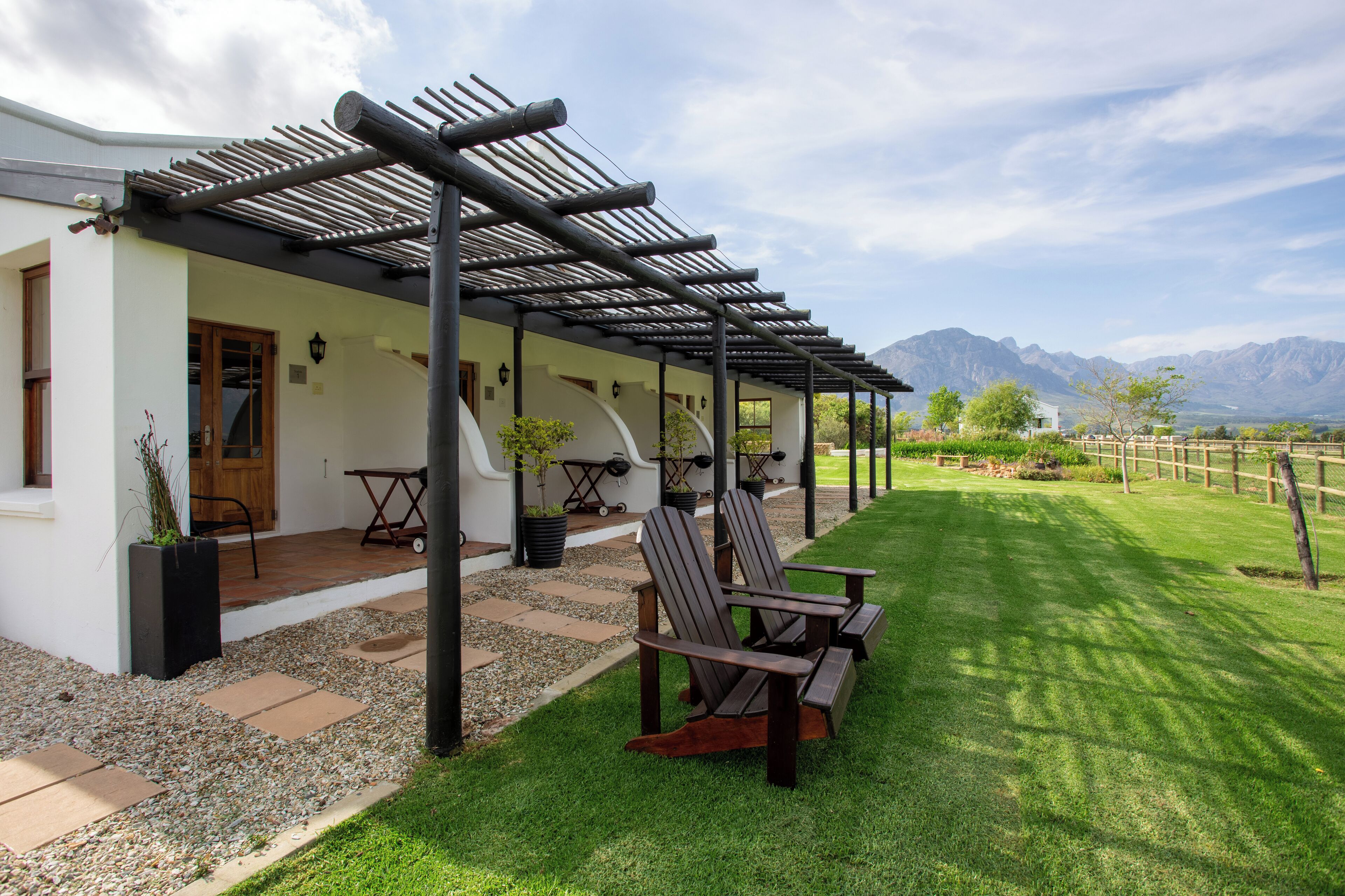 Una casa moderna con un porche cubierto, mobiliario exterior y vistas a las montañas.