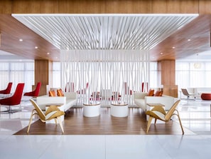 A modern lobby with a central seating area, wooden flooring, and a high ceiling with a unique light fixture. - Novotel Jeddah Tahlia (Jeddah)