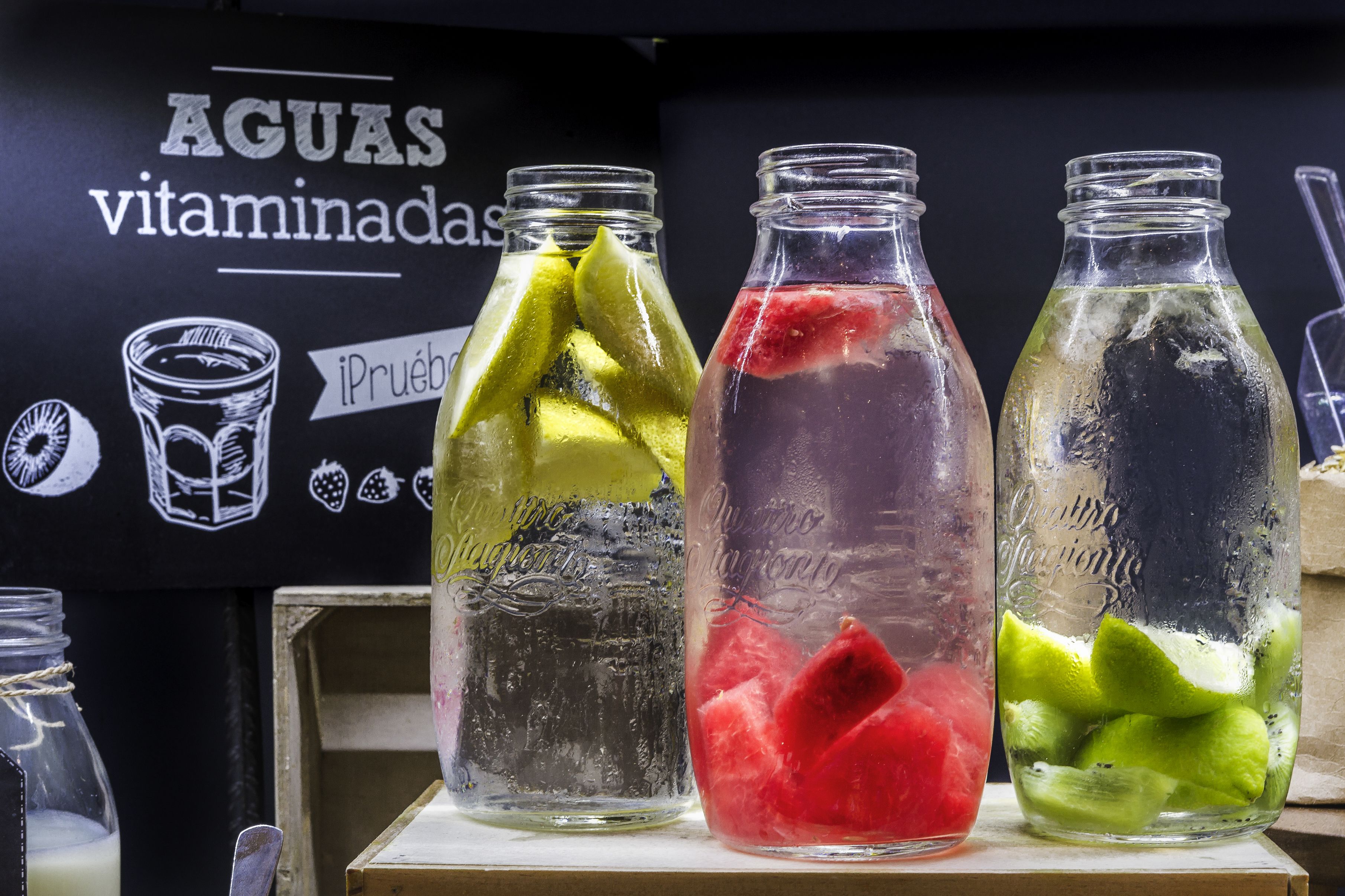 Drei Glasflaschen mit Fruchtscheiben, ein schwarzer Hintergrund mit Text und ein Holzregal.