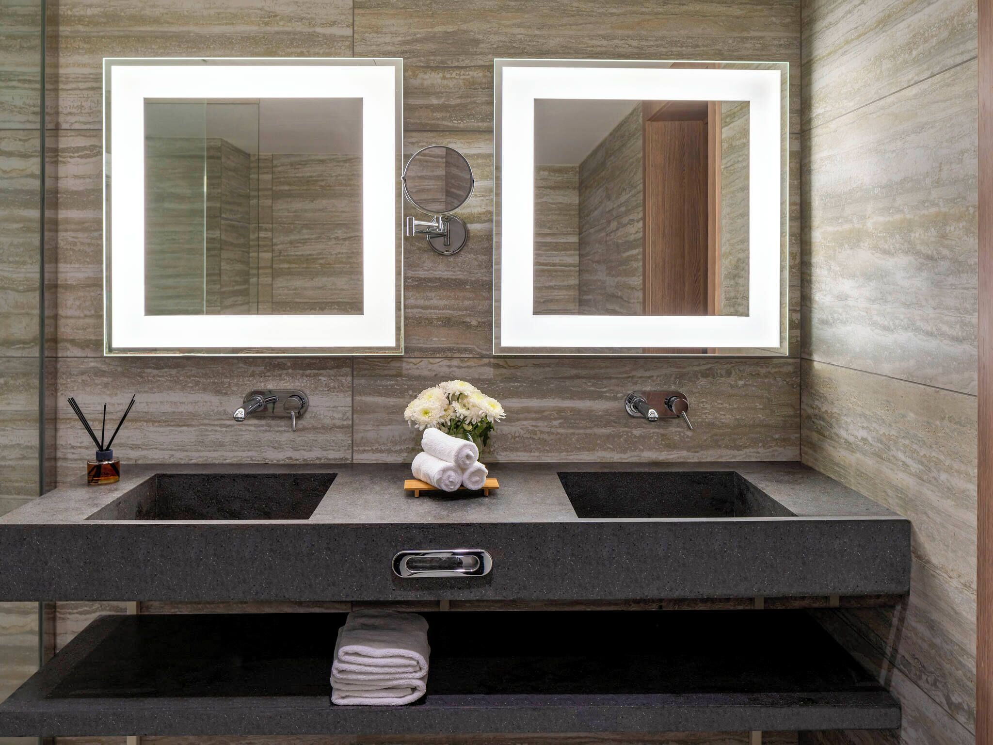 Une salle de bain avec deux lavabos, un miroir et un porte-serviettes.