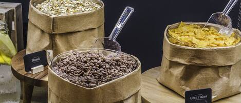 Tres bolsas de papel llenas de diferentes alimentos, cada una con una etiqueta que indica su contenido.