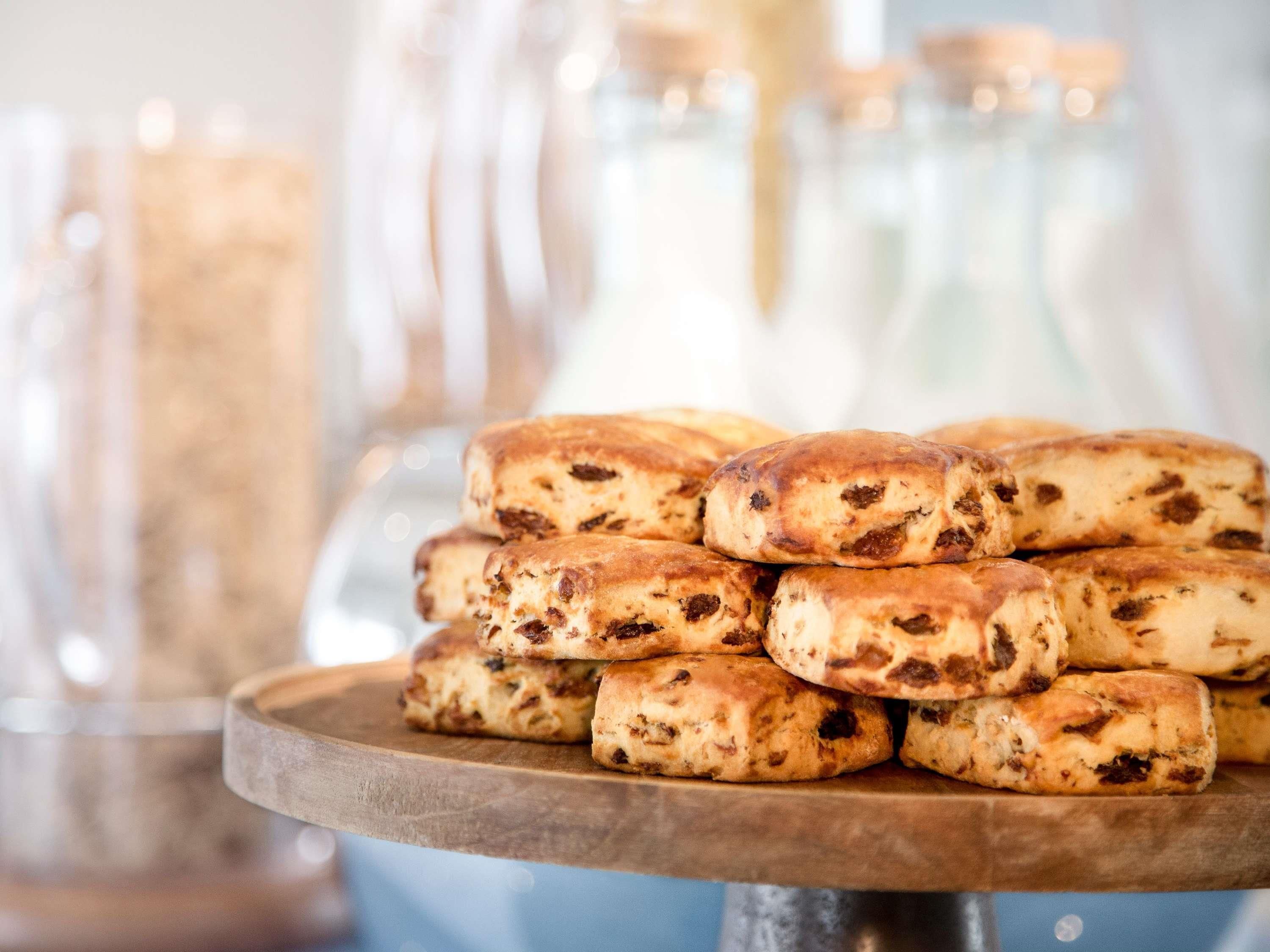 A stack of round, baked goods with visible fruit pieces on a wooden stand.