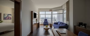 A modern living room with a large window, a sofa, a coffee table, and a TV. - Novotel Jeddah Tahlia (Jeddah)