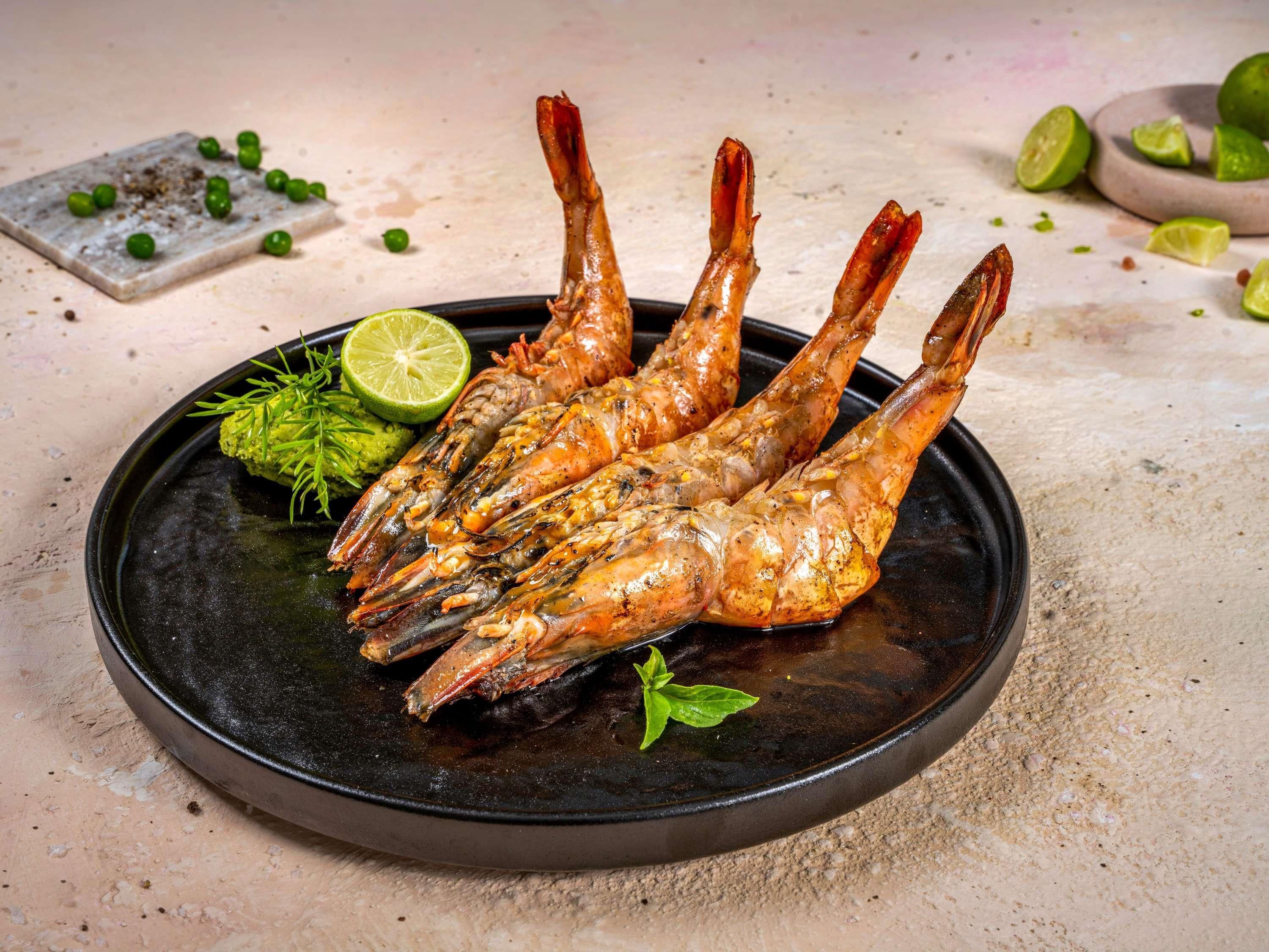 A plate of cooked shrimp with lime and herbs.