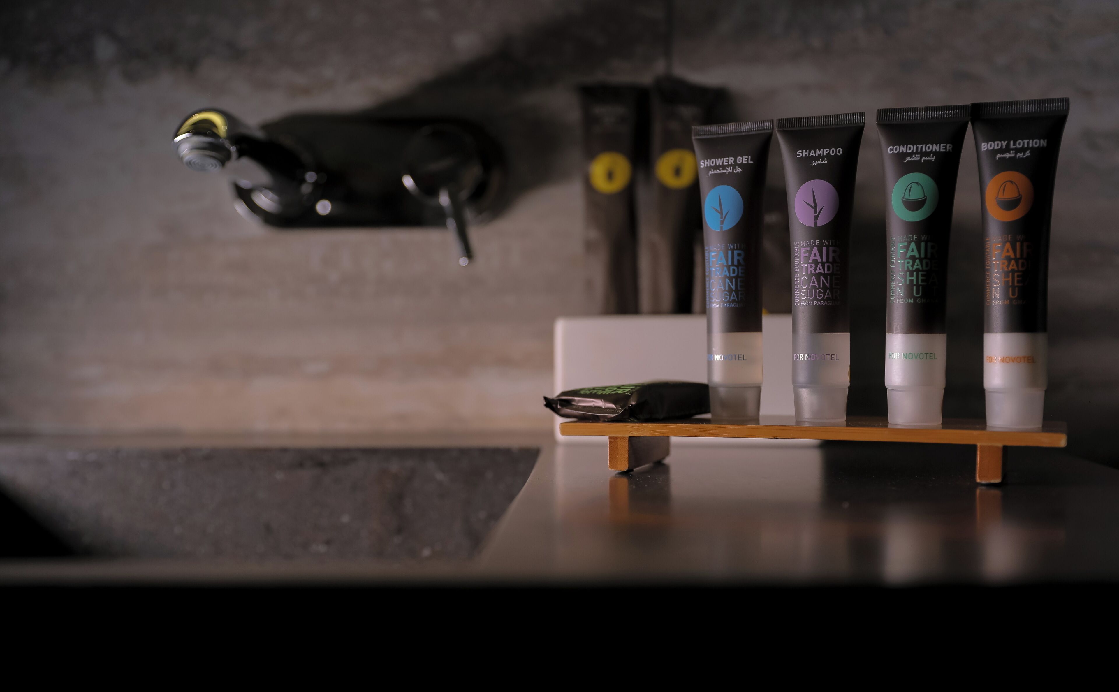 A bathroom with a mirror, a towel rack, and a shelf with toiletries including a shower gel, shampoo, conditioner, and body lotion.