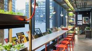 Un bar moderno con una barra larga, taburetes rojos y plantas.